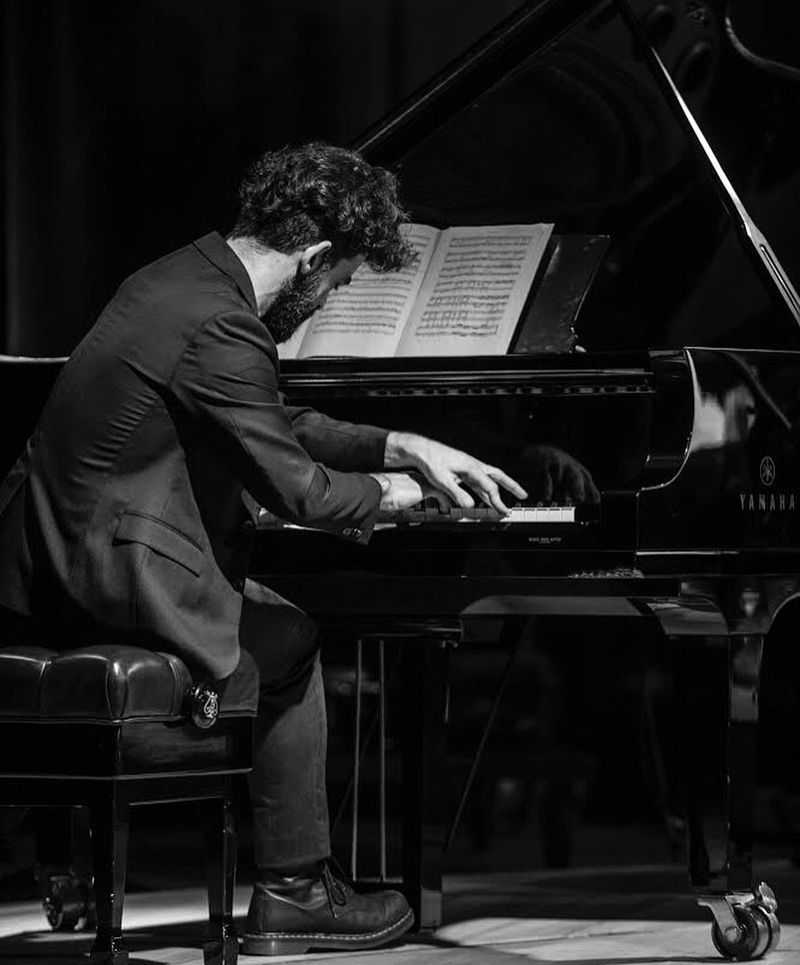 Antonio tocando un piano de cola Yamaha con partitura, en blanco y negro